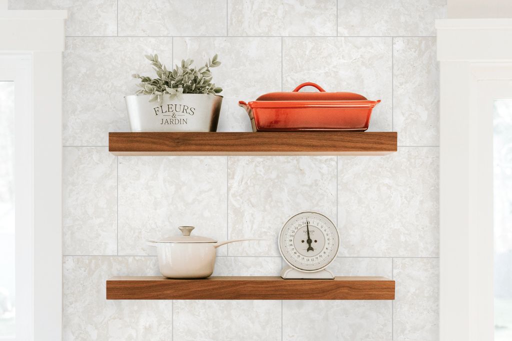 Floating wood shelves styled against a natural stone tile wall, showcasing the timeless beauty of luxury tile from Connecticut Stone's Final Sale Inventory.
